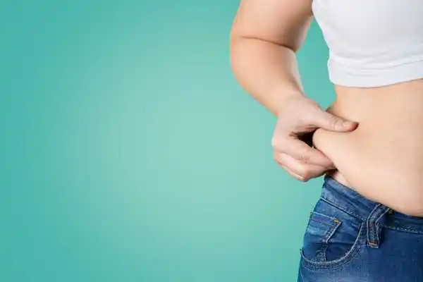 Image of woman pinching her love handles to show weight gain Waltham Forest